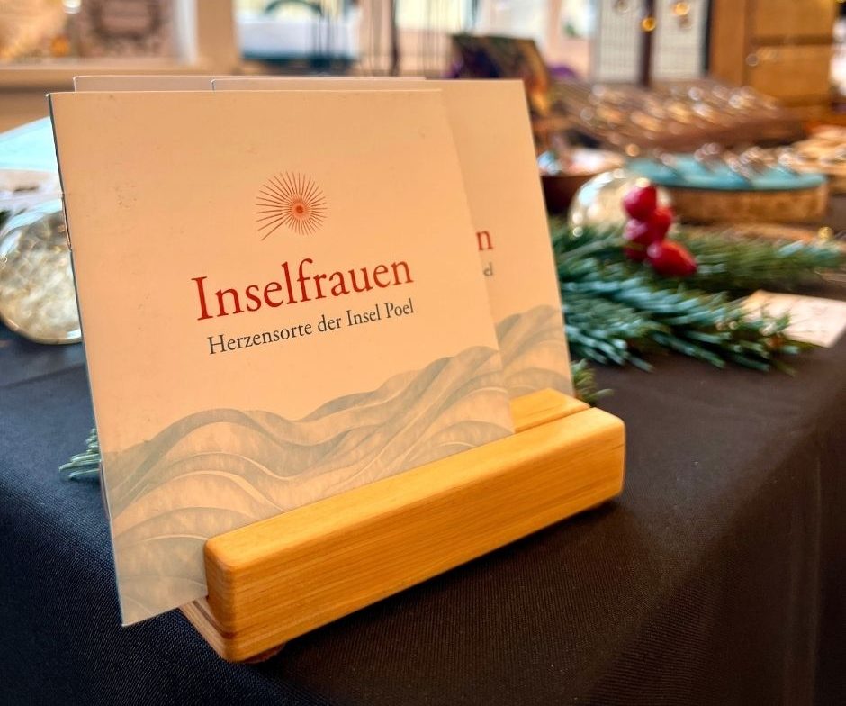 Inselliebe zum Mitnehmen Zwei aufgestellte Broschüren mit dem Schriftzug „Inselfrauen – Herzensorte der Insel Poel“.