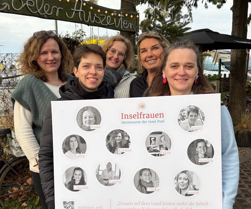 Die Inselfrauen in der Ostseezeitung Gruppenfoto von fünf Frauen, die ein Schild mit den Porträts der Inselfrauen halten.