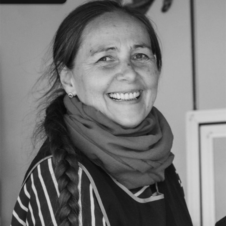Ulrike Heyen Lächelnde Frau mit Zopf, trägt einen Schal und gestreiftes Oberteil.